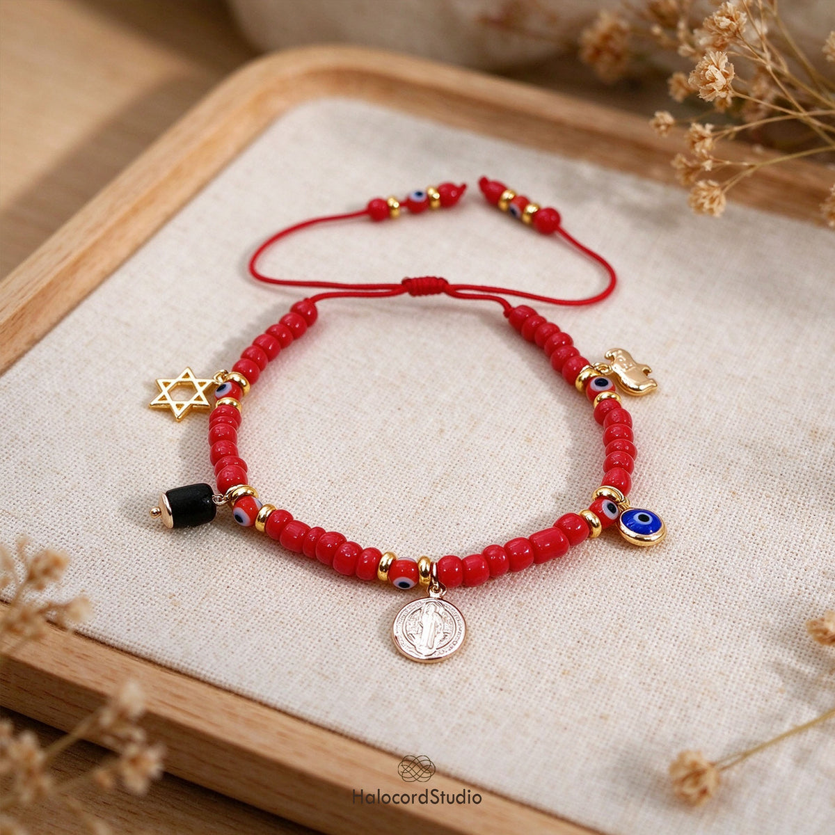 Evil eye red seed bead bracelet with 5 sacred charms on wooden display tray