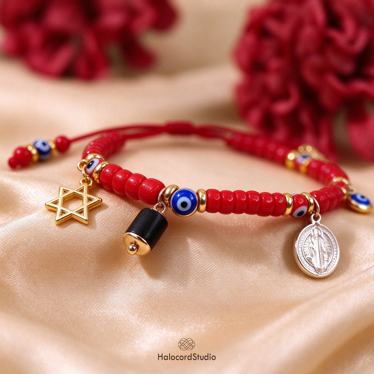 Detailed view of evil eye red seed bead bracelet with charms resting on champagne silk