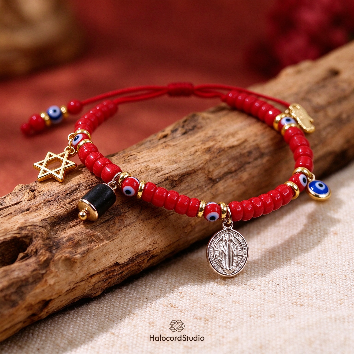 Close-up of red seed bead bracelet showing Star of David and San Benito charms on wood