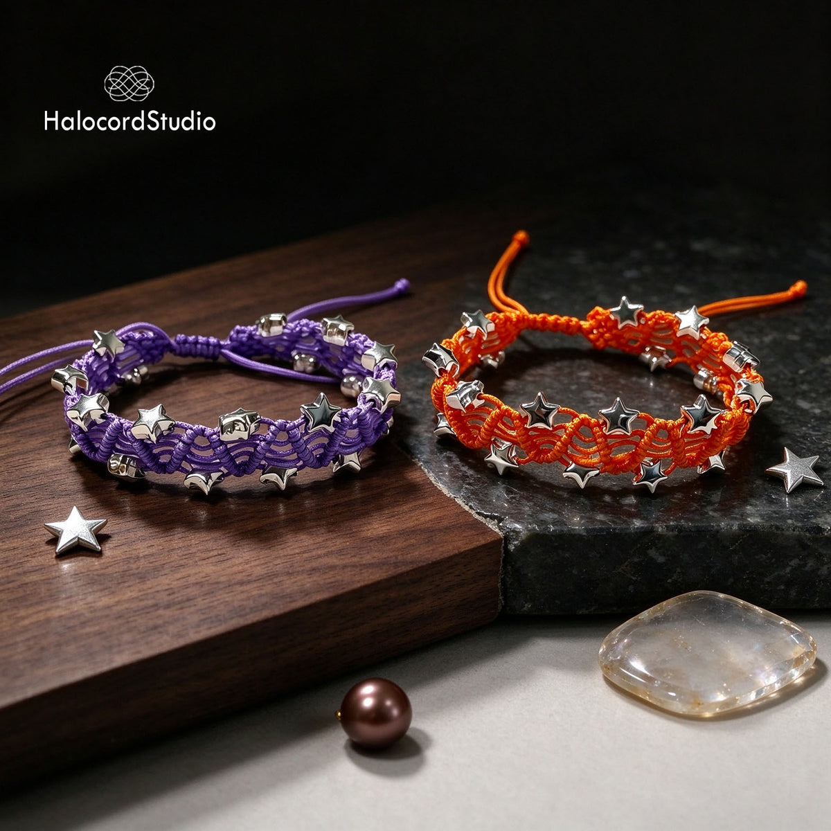 Purple and sunset orange handwoven star charm bracelets paired on a rustic wooden tray