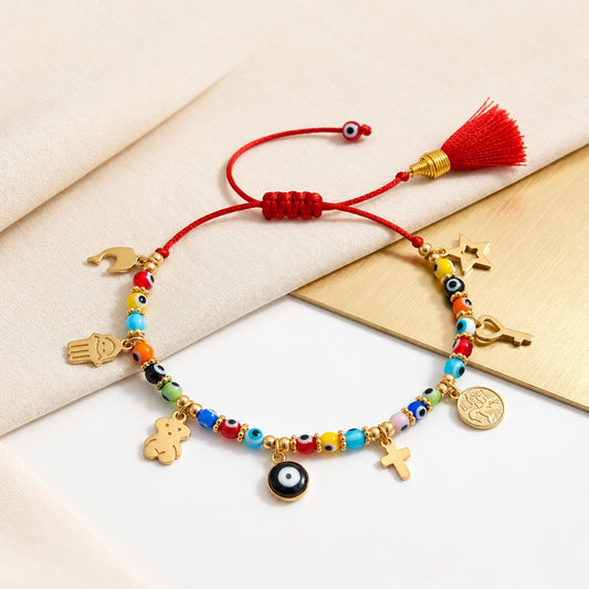 Handmade red string evil eye bracelet with colorful beads, 8 golden lucky amulets, and red tassel on beige cloth