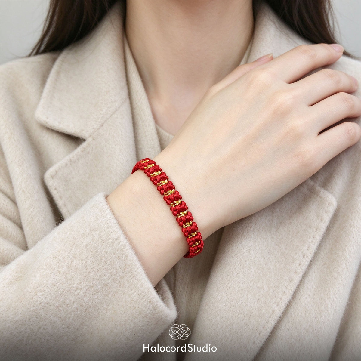 Lifestyle view of the red string bowknot bracelet styled with an elegant beige coat by Halocord Studio