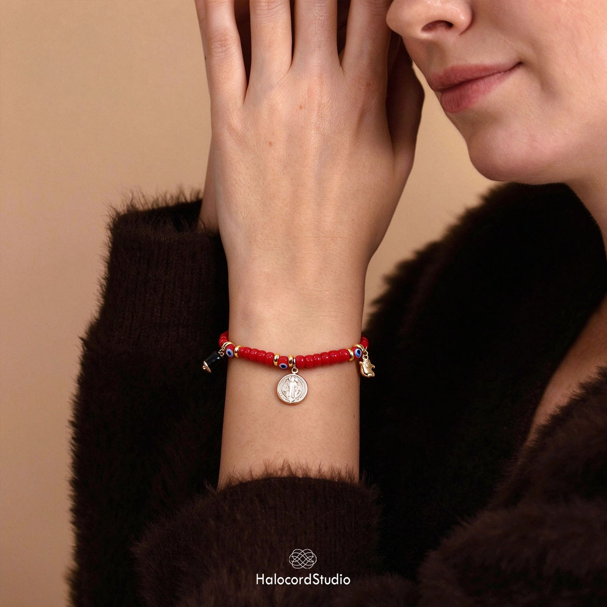Model wearing evil eye red seed bead bracelet with Saint Benedict charm on wrist