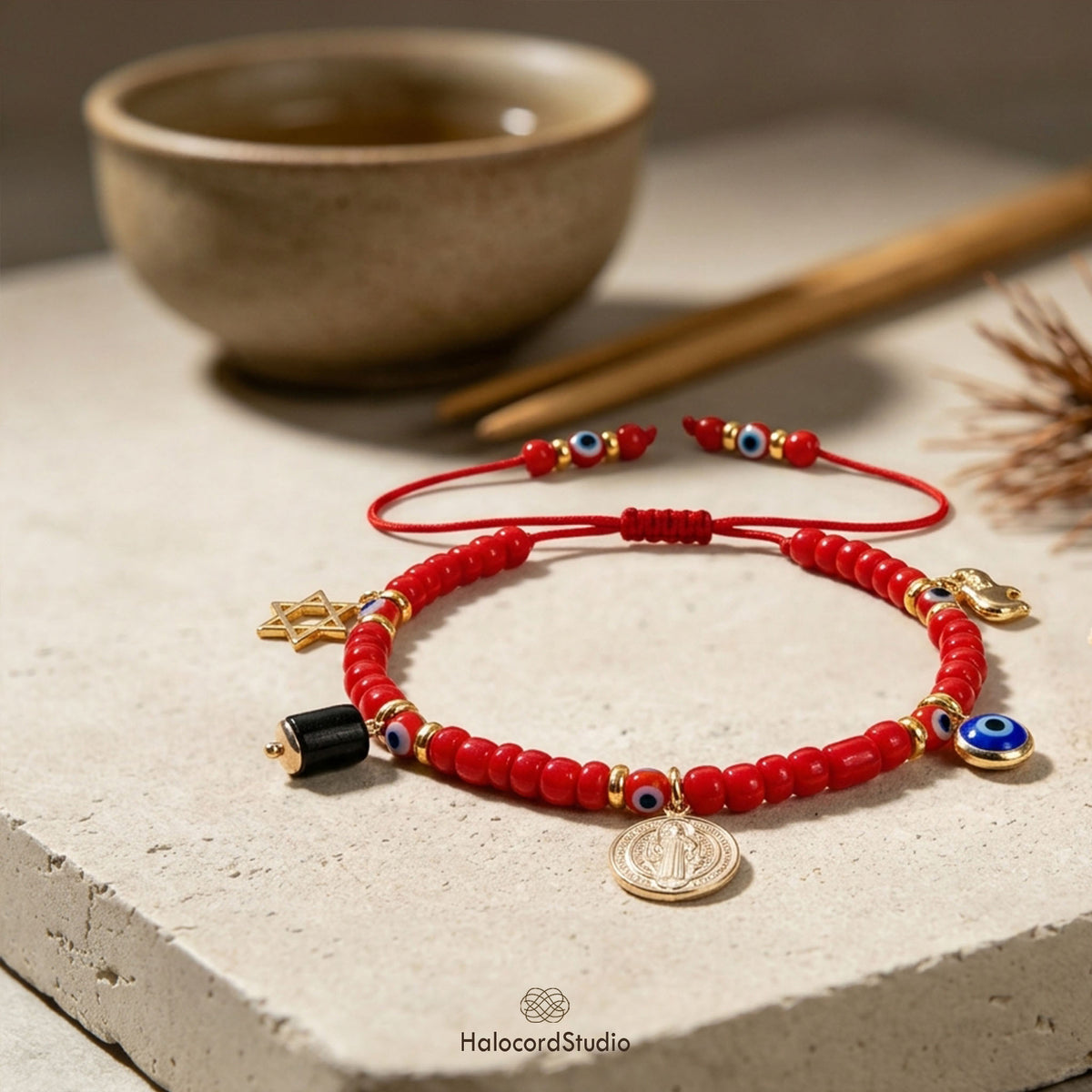 Zen flat lay of red string evil eye bracelet with adjustable knot next to ceramic cup