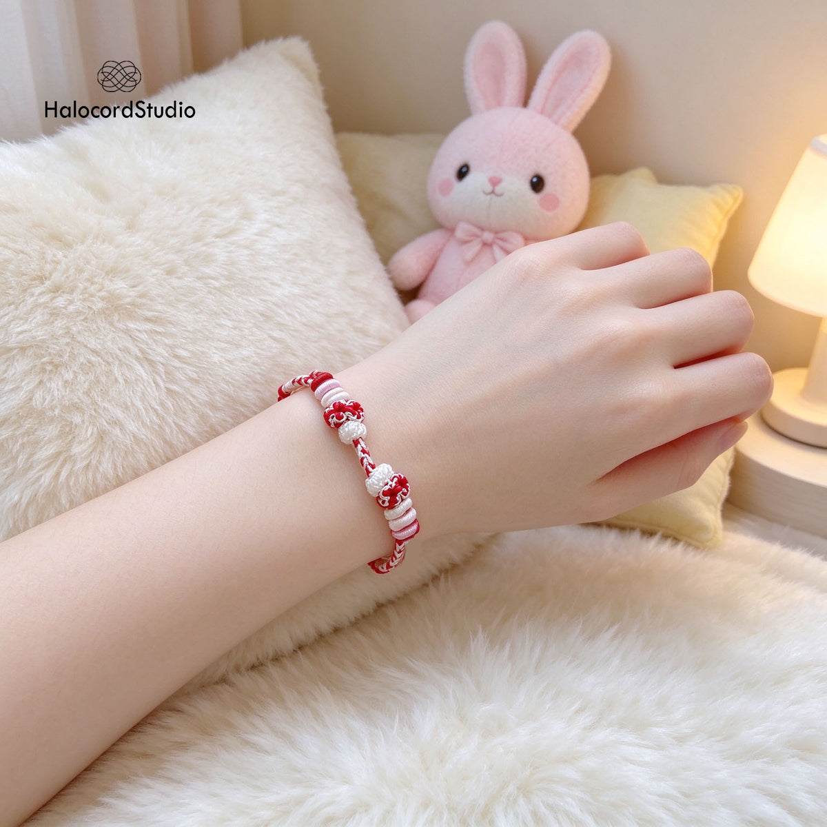  Model wrist wearing adjustable handwoven strawberry cord bracelet beside cute pink plush bunny
