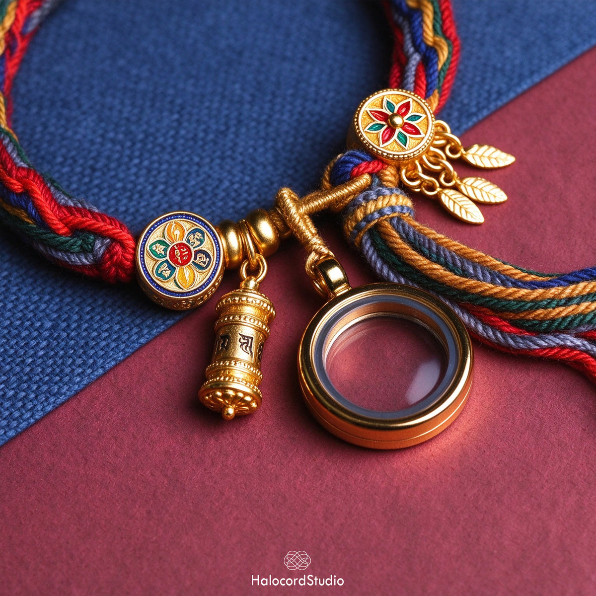 Close-up of golden Gau amulet box, Om Mani Padme Hum prayer wheel, and enamel Dharma wheel bead on braided cord
