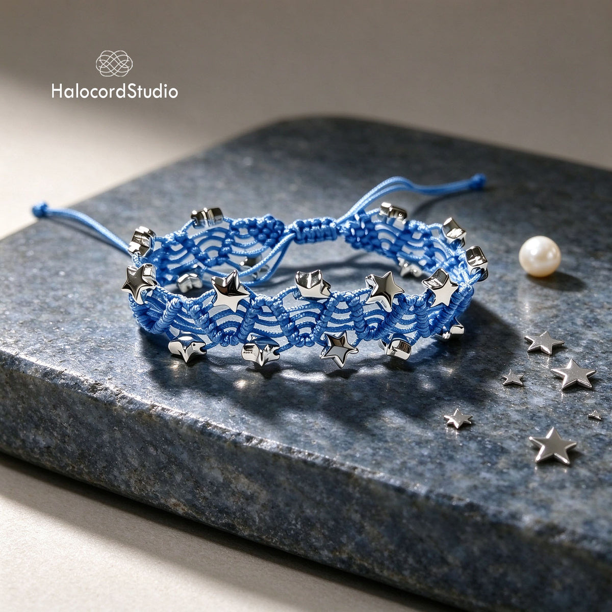 Sky blue handmade star charm woven bracelet with silver-tone star beads on natural slate stone